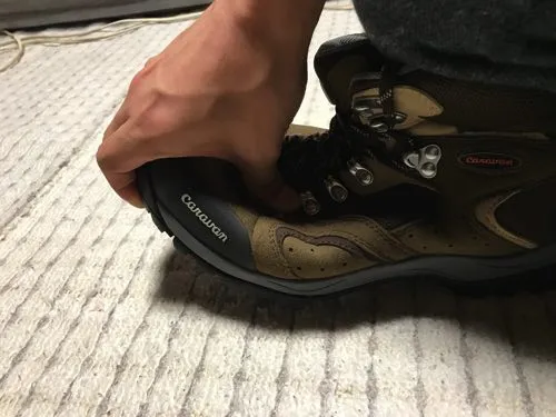 登山靴の底を手で曲げてソールの硬さを確かめている様子の写真