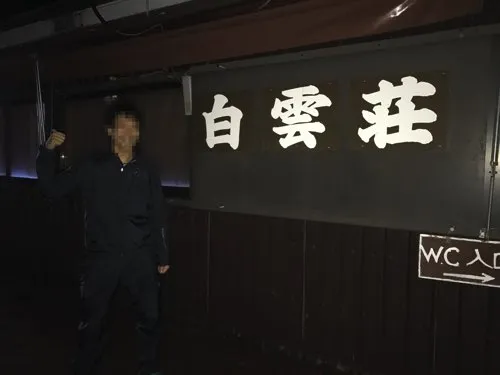 夜の8合目、白雲荘の看板の前で登山者がガッツポーズをしている様子