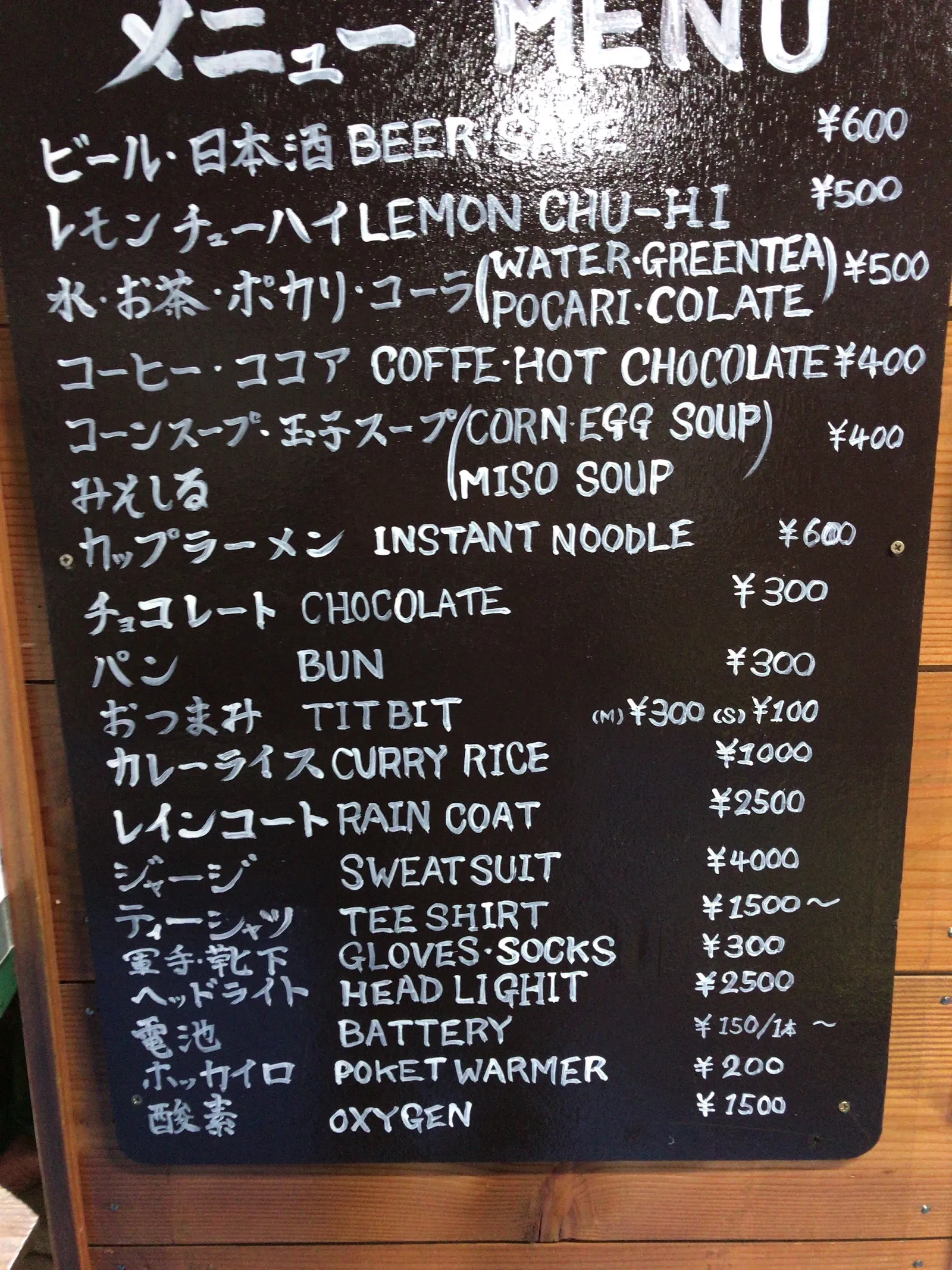 富士山の山小屋の売店に掲げられた手書きの料金黒板。ビールやカップ麺、酸素、水などの値段が書かれている