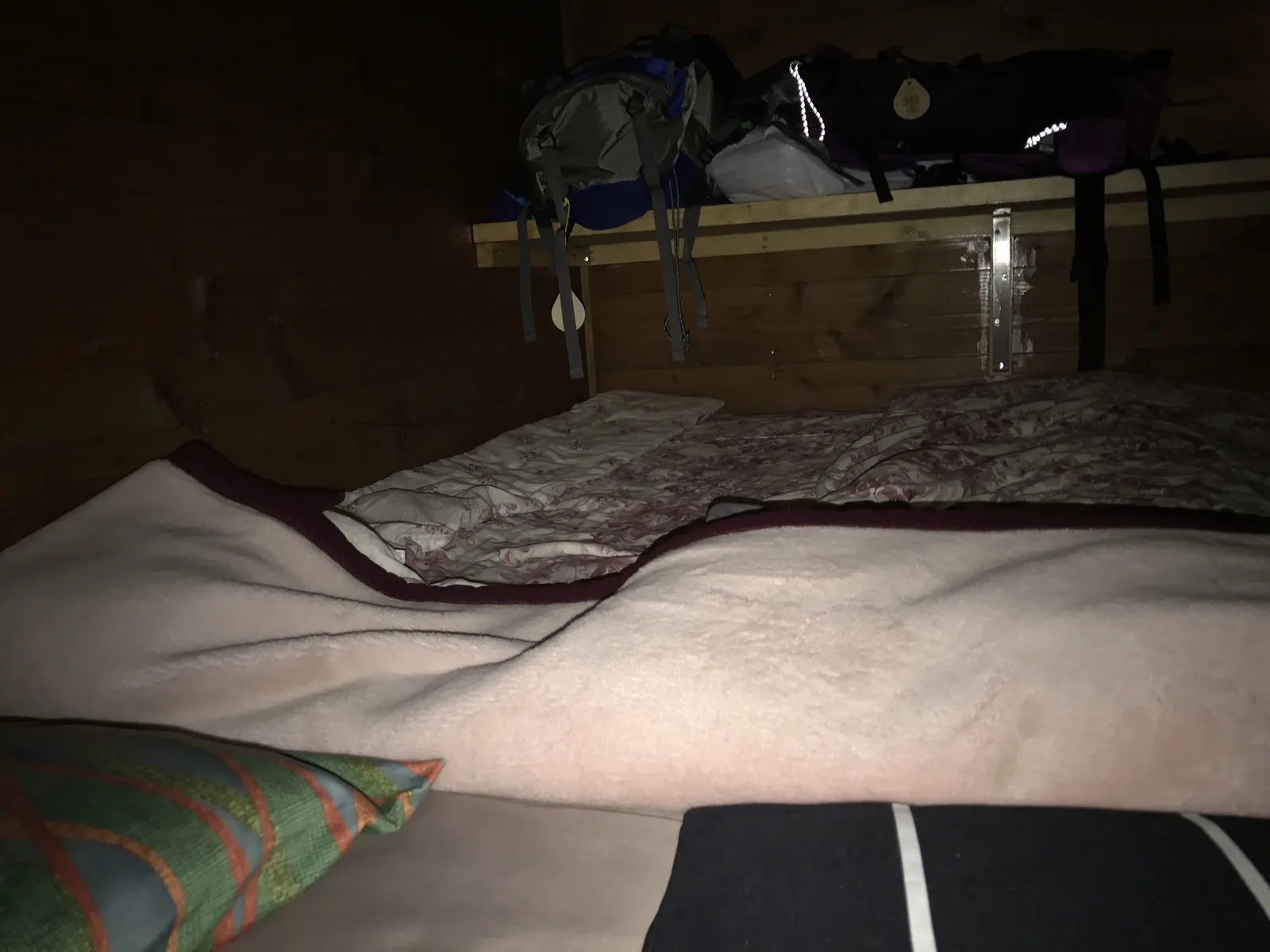 富士山の山小屋の寝床に敷かれた布団と、棚に置かれた登山用ザックの様子