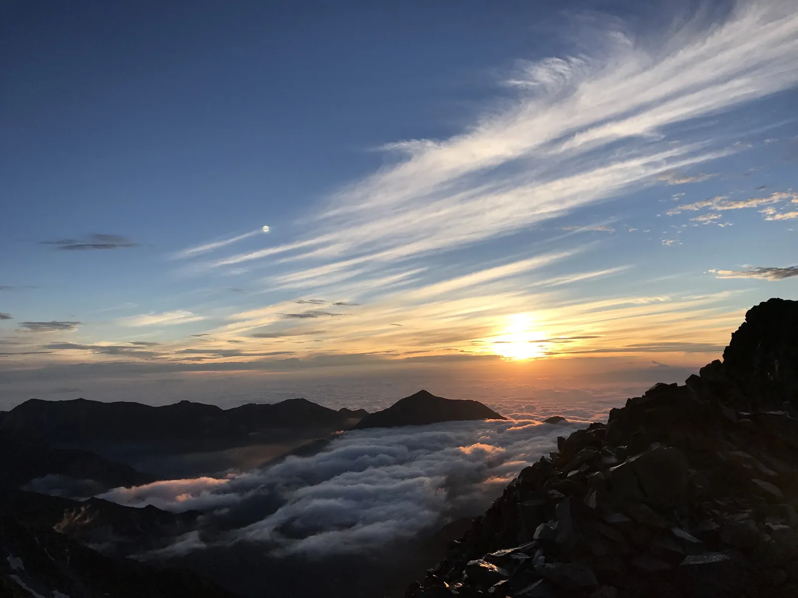 雲海から昇るご来光と流れる巻雲。奥穂高岳山頂から見た日の出