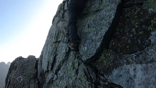 狭い岩の出っ張りに登山靴のつま先を乗せている足元のクローズアップ