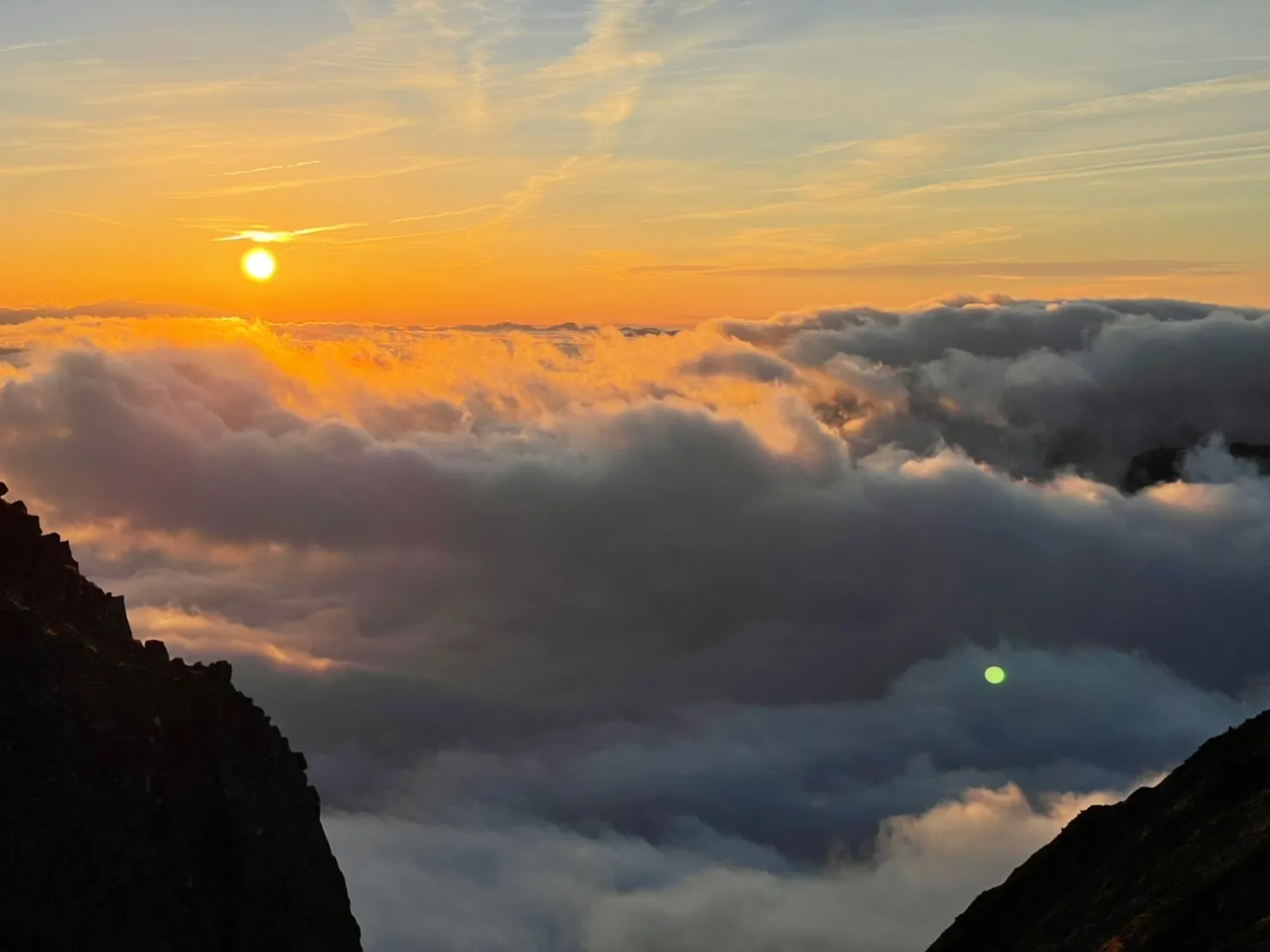 夕方、雲海に沈むオレンジ色の太陽(奥穂高岳〜穂高岳山荘間の稜線から撮影)