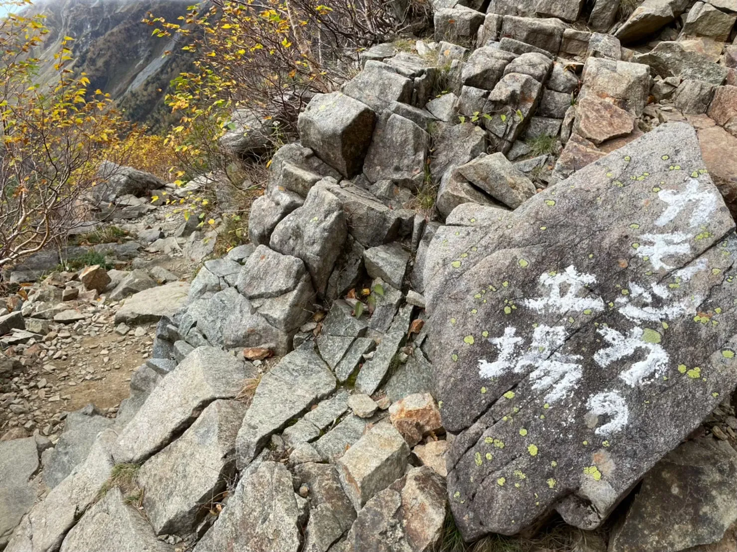 白いペンキで「カモシカの立場」と書かれた大岩と、その先に続く岩がちの登山道