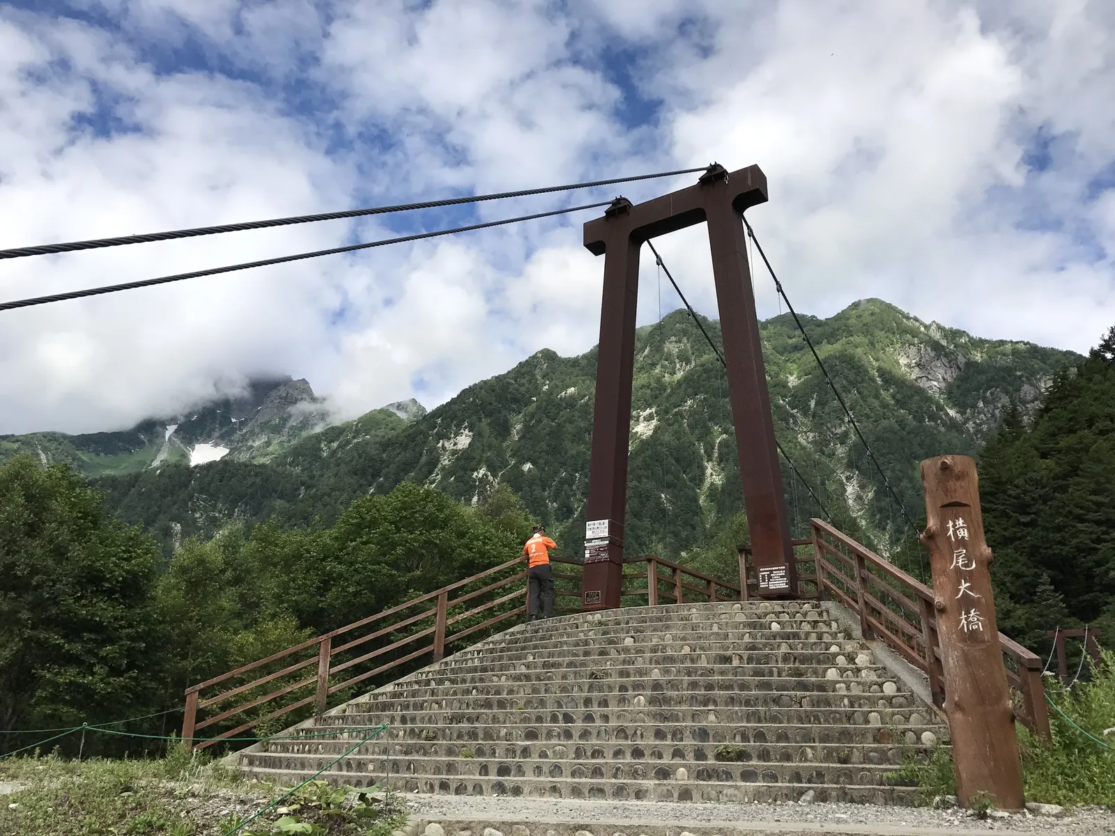 銘板の付いた横尾大橋と、その奥に見える岩峰。涸沢ルートへの分岐点になっている