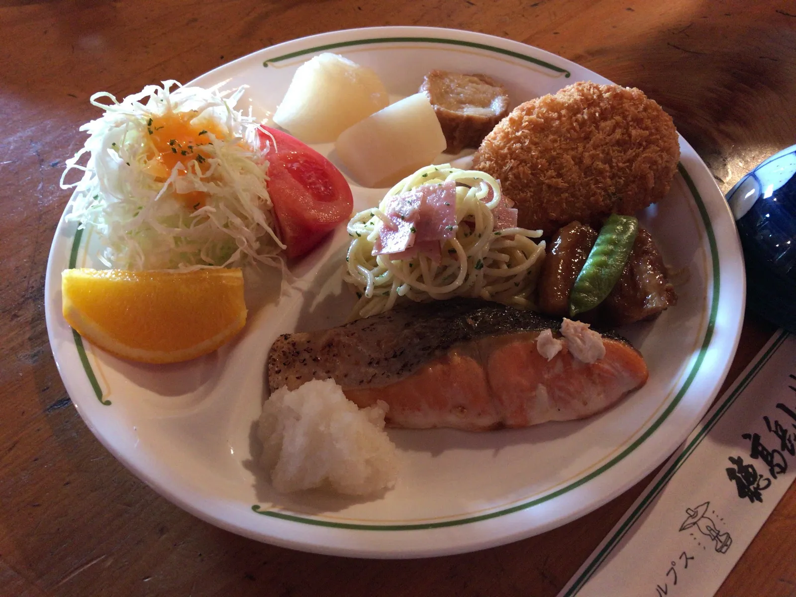 穂高岳山荘の夕食に出された焼き魚とコロッケ、サラダ、オレンジが並んだプレート