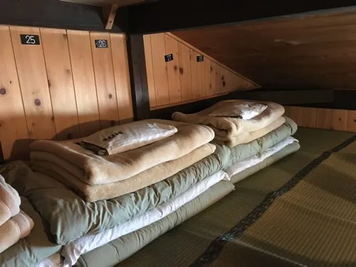 番号札が付いた山小屋の寝床に敷かれた布団と毛布